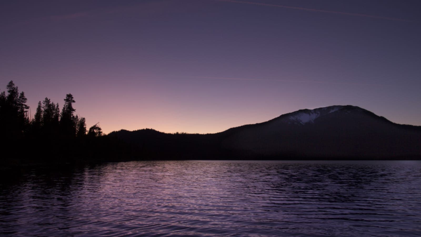 Un lac calme au crépuscule au pied d'une montagne