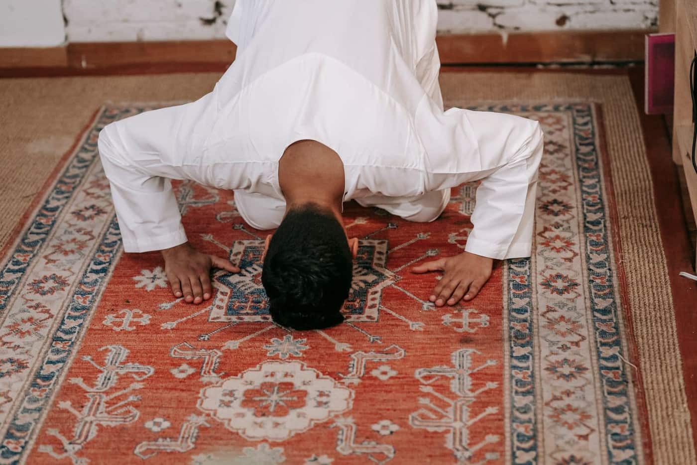 A worshipper sitting alone in a softly lit mosque