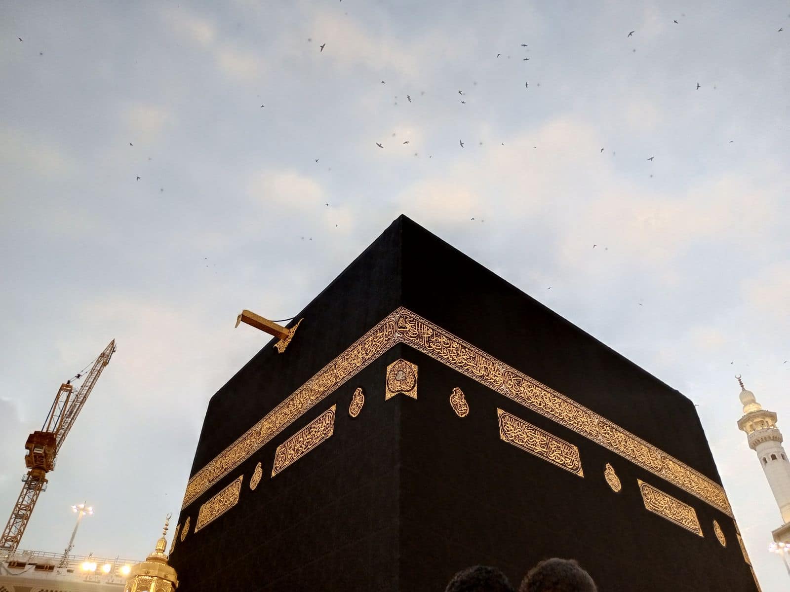 The Kaaba at dusk, birds in the sky above