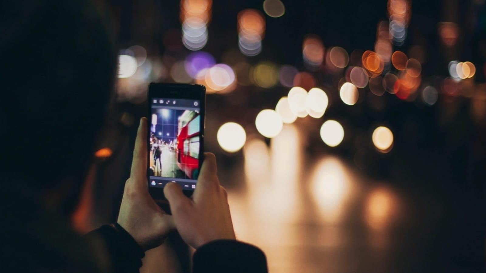 A hand holding a smartphone at night